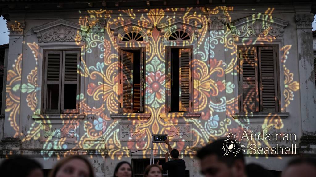 Close view of projected Peranakan patterns moving across an old Phuket facade